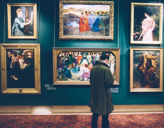 A man appreciating artwork in a museum, captivated by the beauty and creativity of the paintings on display.